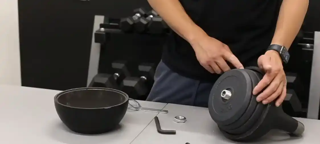 A man is setting the weights of Bells Of Steel Adjustable Kettlebell.